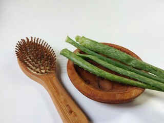 Aloe vera and wooden hair comb with loss hair on the wooden plate isolated on white background....