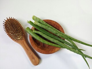 Aloe vera and wooden hair comb with loss hair on the wooden plate isolated on white background....