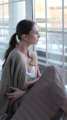 Beautiful young girl posing for the camera while sitting near a large window