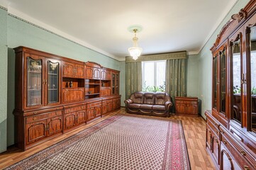 cozy living room with antique wooden furniture, including a large cabinet and a brown leather sofa,...