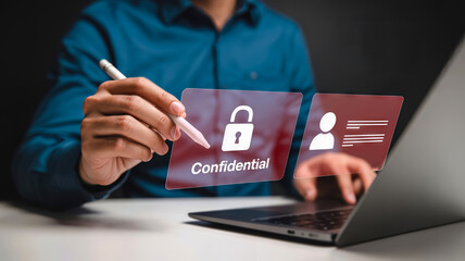 A person touches a confidential screen with a lock icon, highlighting data security and personal information protection while using a laptop