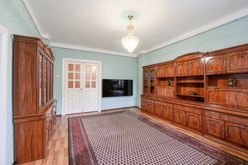 living room features dark wood furniture, a large patterned rug, and a chandelier. A flat screen TV...