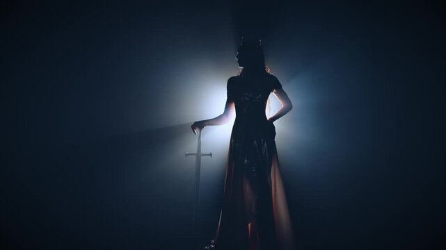 real person fashion model posing, dark silhouette fantasy woman queen holds sword in hands. Black room full smoke night blue moon light fog backlit. Gothic girl elf warrior standing with sharp blade