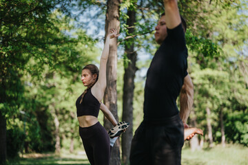 A man and woman perform exercises and stretches together in a peaceful outdoor park.