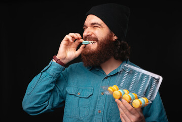 A young man happily plays with a colorful toothbrush and medication bottles, highlighting selfcare...