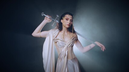 real person fashion model posing stong face eyes looking at camera, fantasy woman queen holds sword in hands. Black dark room full smoke night moon light fog. Gothic girl elf warrior with sharp blade - Powered by Adobe