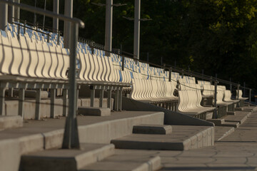 A long row of bright white benches is neatly lined up along a bustling sidewalk, providing seating...