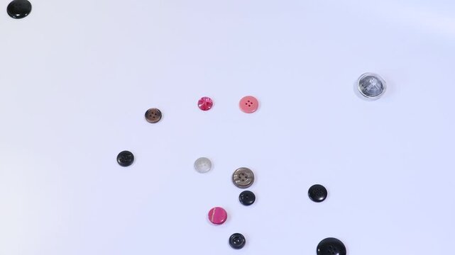 A woman holds a handful of buttons in her hand and throws them on the table