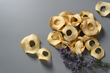Dried apple slices arranged artfully with lavender sprigs on a soft gray background showcasing...