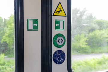 Train door panel with essential safety warning signs, clear exit arrows, and passenger assistance...