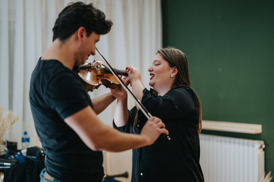 Music teacher assisting a student with violin playing technique during a focused lesson indoors