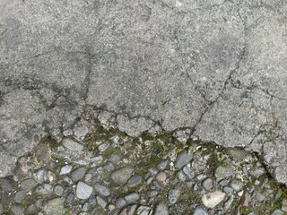 Cracked Concrete Surface with Exposed Pebbles and Moss. Close-up of aged, cracked concrete...