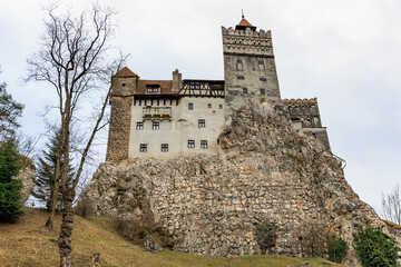 Majestic bran castle on rocky hill surrounded by leafless trees