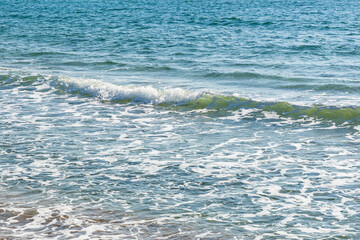 Gentle ocean waves lapping on sandy shoreline under clear blue sky