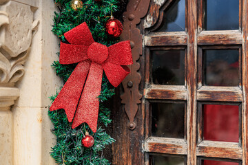 Festive christmas wreath with red bow and baubles on rustic wooden door