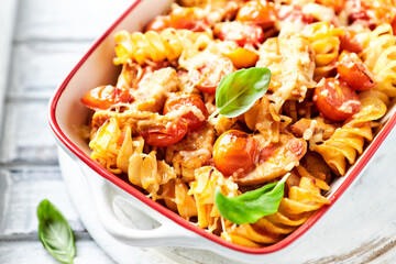 Pasta with chicken breast, cherry tomatoes and fresh basil. Bright wooden background. Close up.	
