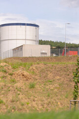An industrial storage tank is positioned adjacent to a recently cleared field, beautifully framed...