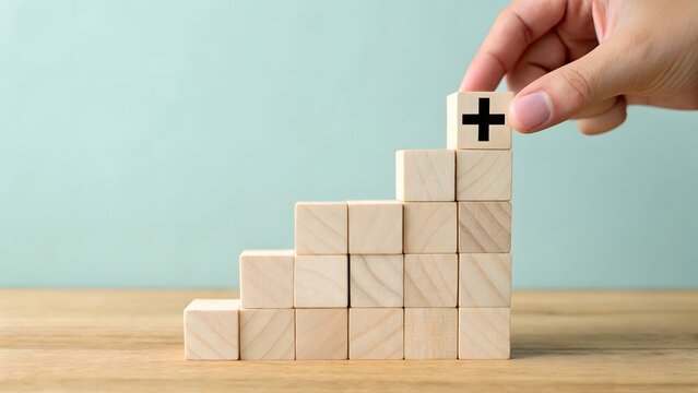 Hand stacking wooden blocks to create a growth staircase with a plus sign
