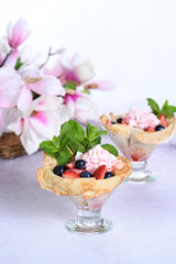 Cooking French pancakes with whipped cream filling with strawberries and blueberries, strawberry syrup, almond petals. Served in a glass and garnished with mint. 