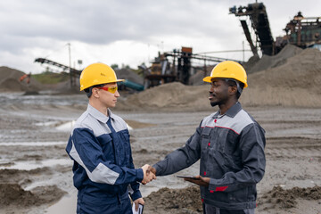 Mining surveyors in hard hats shaking hands at sand quarry site, industry Portrait worker