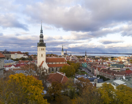 Aerial view of the spire of St. Olaf's Church rises above the medieval cityscape, with the Baltic Sea shimmering in the distance, Tallinn, Harju County, Estonia.
