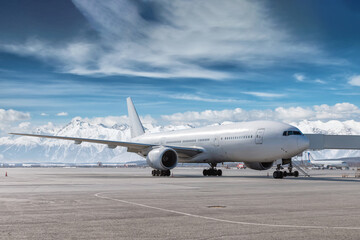 Modern white wide body passenger jet plane at the airtube at winter airport on the background of high snow capped mountains