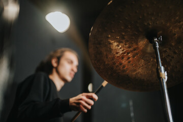 A musician practices playing drums with intense focus in a moody and artistic studio ambiance.