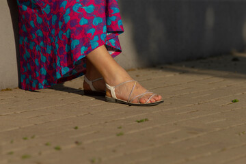 This image features a closeup view of a womans foot, elegantly adorned with a stylish sandal,...