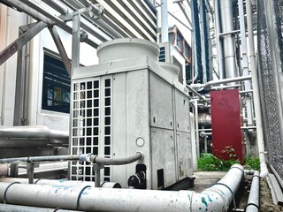pipes and valves. Industrial HVAC outdoor units with visible copper piping and weathered surfaces,...