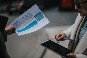 Two individuals collaboratively discussing progress and data, utilizing a digital tablet and a...