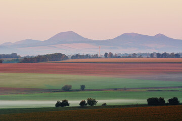 Czech Fields Layer with Morning Mist and Distant Hills Silhouettes