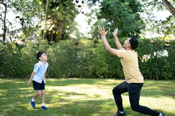 Father and Son Playing Soccer Together in Garden