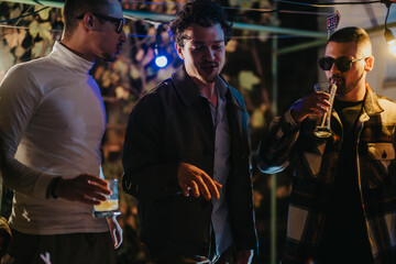 A group of friends socializing and sharing drinks outdoors during a cozy evening celebration.