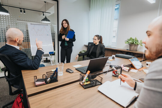 Group of colleagues discussing ideas at a meeting table with charts and laptops in a modern workplace