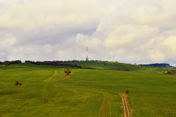 Hazy Meadow Landscape with Hills and Path Under Cloud Cover