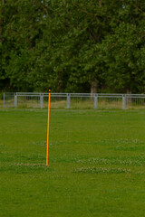 A tall yellow pole stands proudly in the center of a beautifully lush green field that stretches out all around it