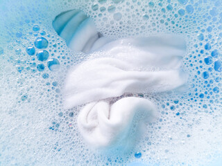 White fabric soaked in detergent water in a basin, illustrating a laundry and cleaning concept.