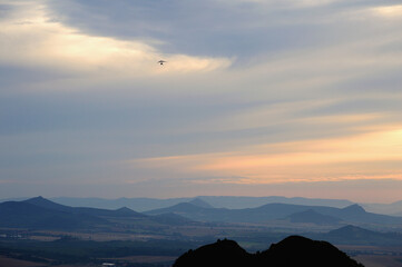 Morning Clouds and Hill Silhouettes with Hang Glider in Flight