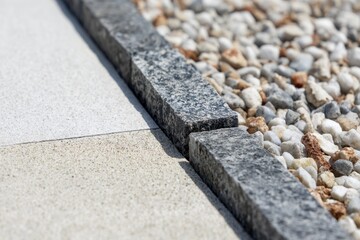 A close-up of the edge between paver and gravel, showing that there is no clear line or crack in between the two materials Generative AI