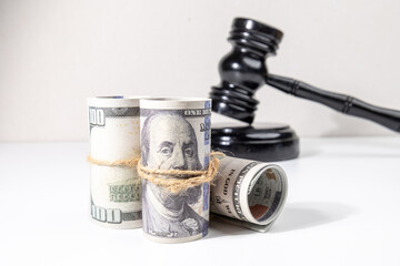A gavel set behind bundles of money conveys the concept of financial consequences, court verdicts,...
