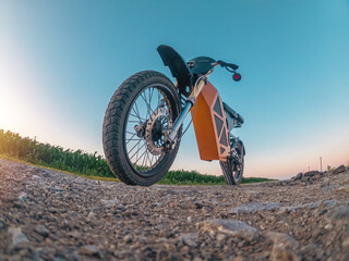 Creative photo of zoomed electric motorcycle low angle view. Arcing horizon with blue sky.