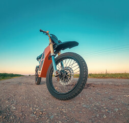 Scooter, electric motorcycle. Environmentally friendly transport. Front view. Rural road at sunset.