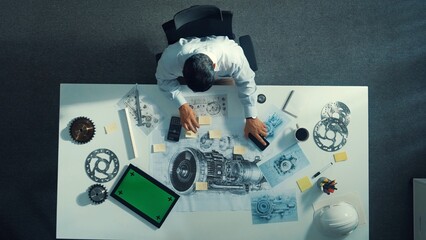 Top down view of skilled engineer writing and planning turbine engine design while sitting at...