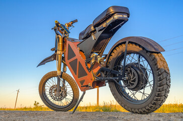 Electric motorcycle, electric bike. Modern ecofriendly transport. Side view. Rural road background.