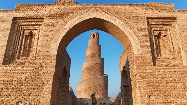 Historic view of Abu Dulaf Mosque in Samarra, Iraq, featuring its iconic spiral minaret and vast Abbasid-era architecture surrounded by desert landscape.