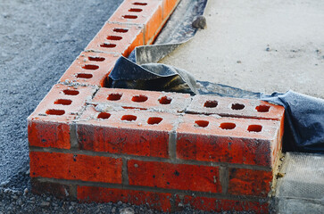 Close-up of red brick wall top covered with frost and on a cold winter day