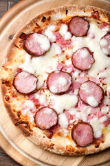 Pizza with sausage, ham and mozzarella cheese on wooden background. Soft focus. Close up	