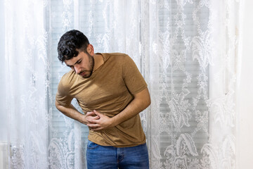 Obraz premium Man clutching abdomen in pain possibly from spleen or appendix issue on white background
