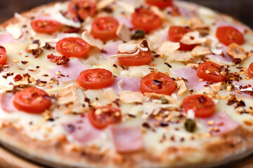 Pizza with ham, cherry tomatoes and mozzarella cheese. Wooden background. Soft focus. Close up.	