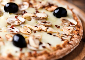 Pizza with champignons, black olives and mozzarella cheese. Wooden background. Soft focus.	